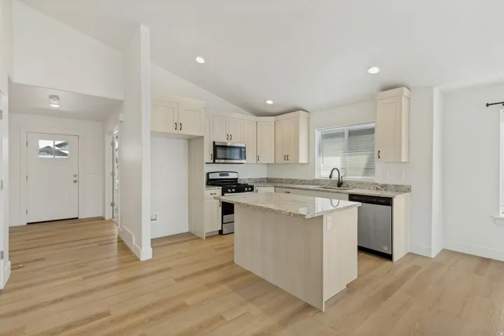 Kitchen featuring light wood-finish cabinetry, a central island, stainless steel appliances, and granite countertops