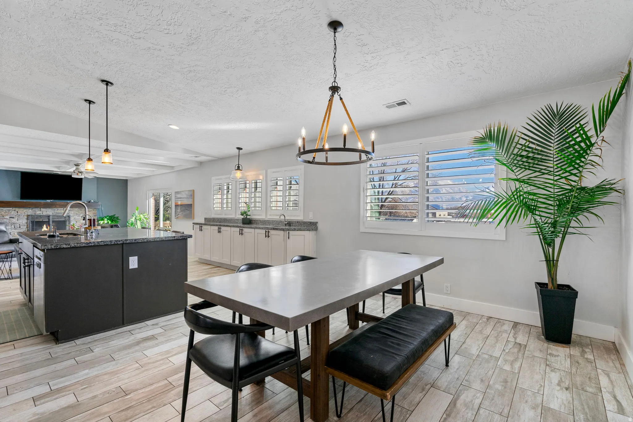 Spacious kitchen and dining area featuring wood-finish flooring, a large island with a stone countertop, and pendant lighting