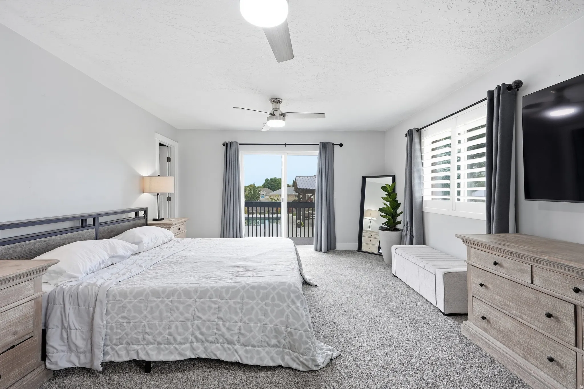Spacious primary bedroom with ensuite access to a private balcony, ceiling fan, and abundant natural light