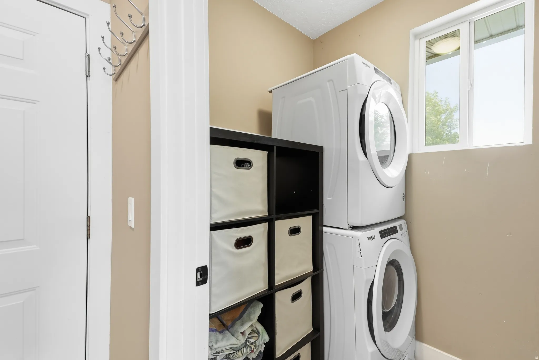 Dedicated laundry area with stackable appliances and an integrated storage unit