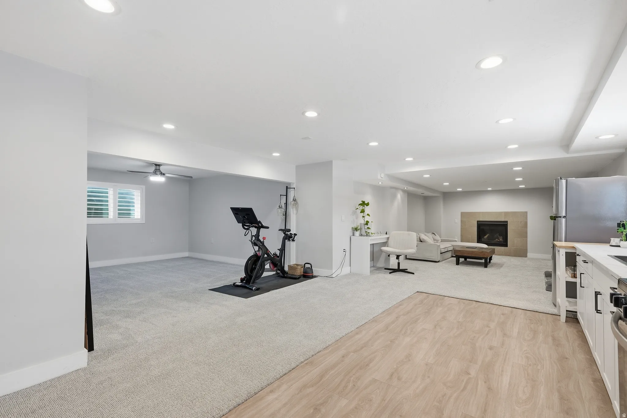 Recessed lighting throughout, wood-finish flooring, carpeted areas, a ceiling fan, and a built-in fireplace with a hearth