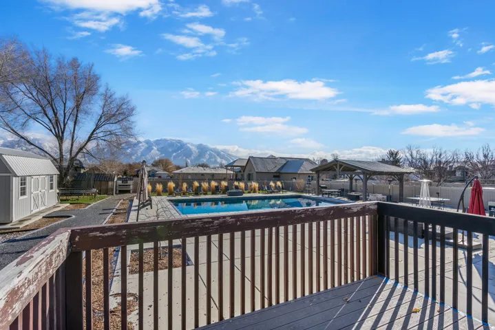 Expansive outdoor deck with a private swimming pool, concrete pool surround, built-in gazebo, and mountain backdrop