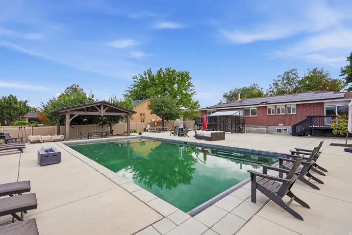 Sparkling resort-style swimming pool with geometric hardscape decking, complemented by Adirondack lounge seating and mature landscaping