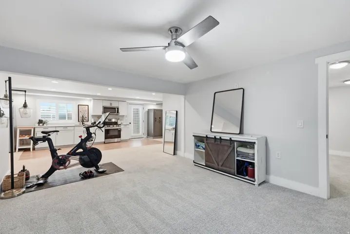 Recessed lighting, wood-finish flooring, white cabinetry, stainless steel appliances, and a ceiling fan with integrated lighting