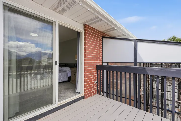 Balcony featuring composite decking, brick exterior wall, and privacy screening