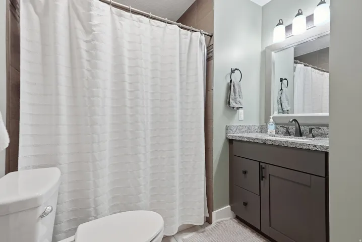 Contemporary bathroom featuring a dark wood-finish vanity with dual-sink configuration, granite countertop, and polished chrome fixtures