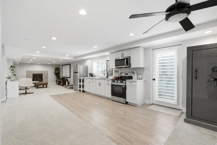 Open-concept living space with recessed lighting, a fireplace, and a kitchen featuring white cabinetry and stainless steel appliances