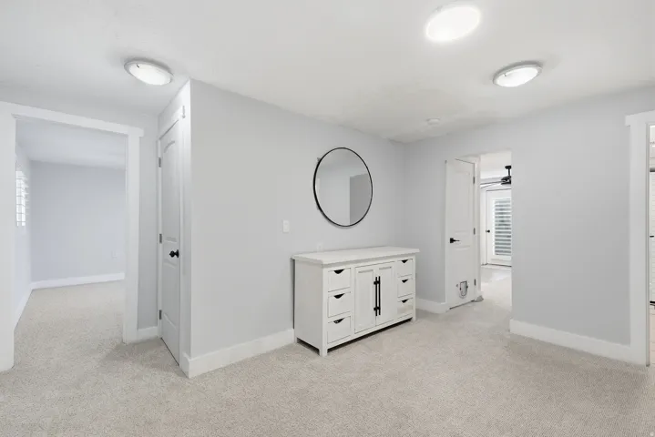 Spa-inspired primary bathroom featuring a white vanity with multiple drawers and brushed nickel hardware, neutral tile flooring, recessed ceiling lighting, and an oval mirror with black metal frame