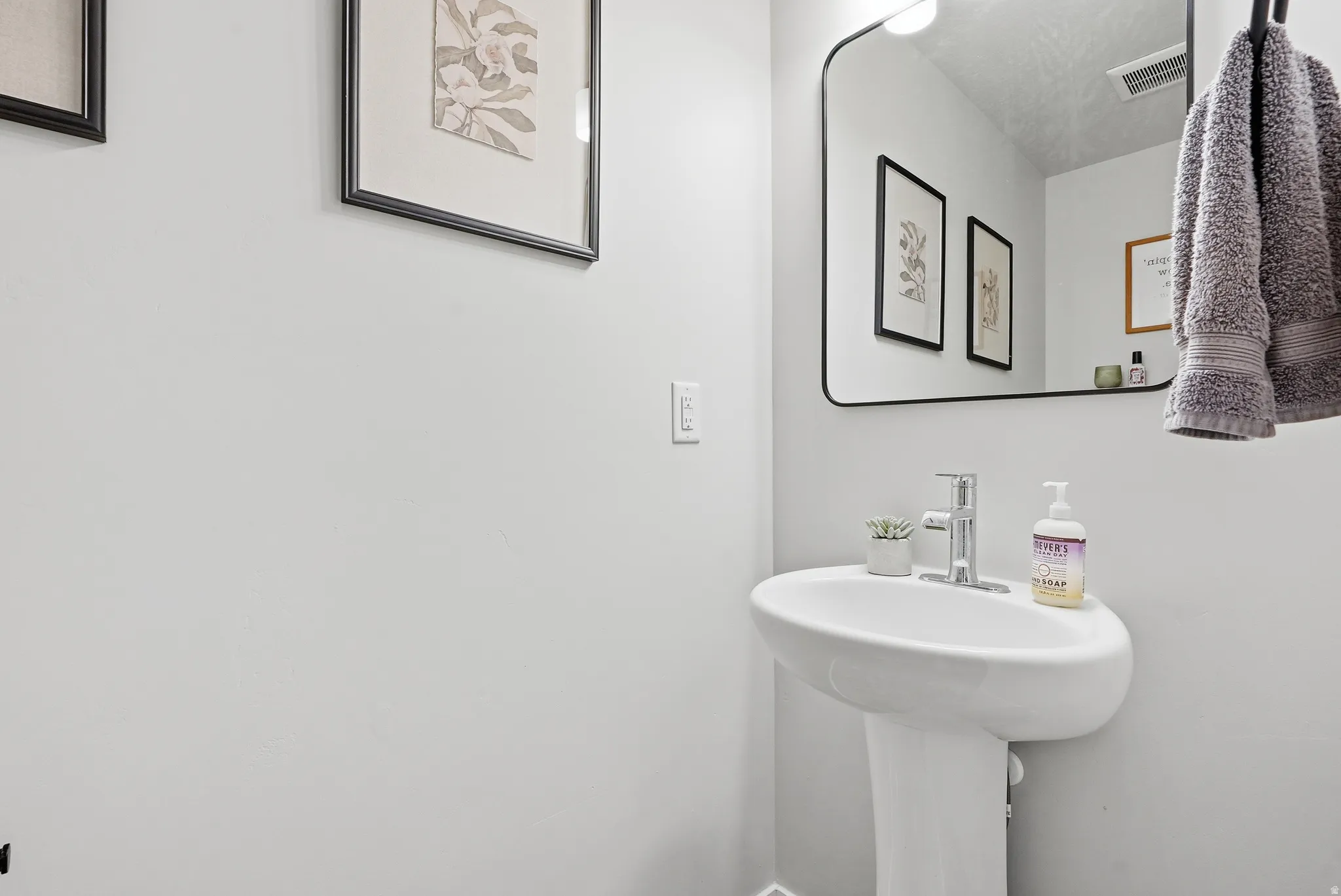 Pedestal sink with a polished chrome faucet, set against light-toned walls