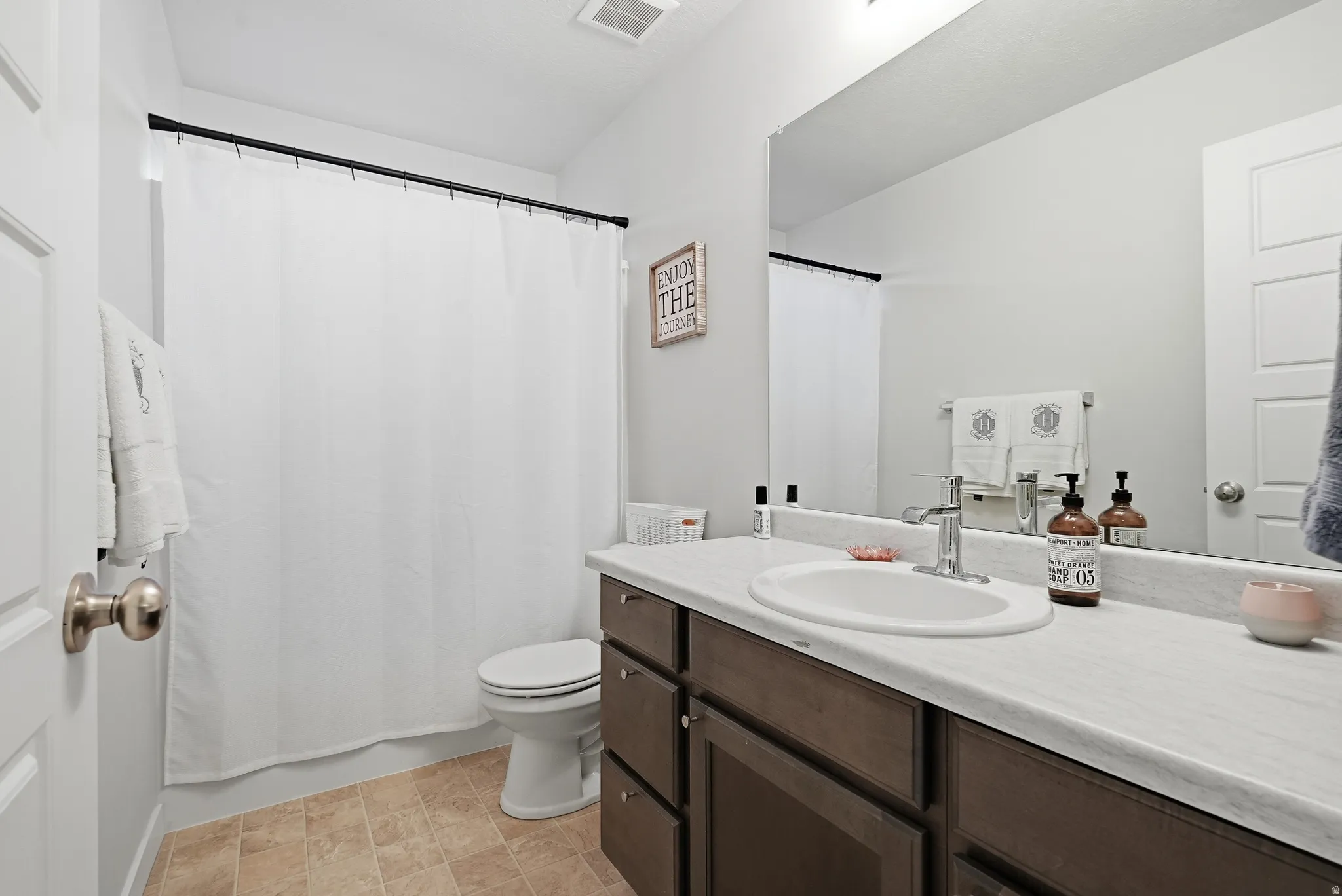 Vanity with a built-in sink, chrome-finish faucet, and an expansive mirror
