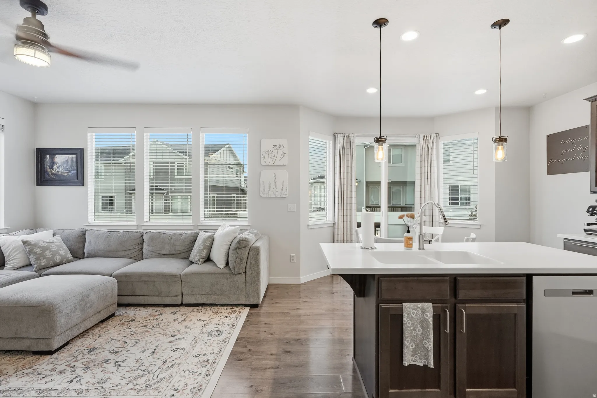 Open-concept living space with wood-finish flooring, recessed lighting, and ample natural light from multiple windows