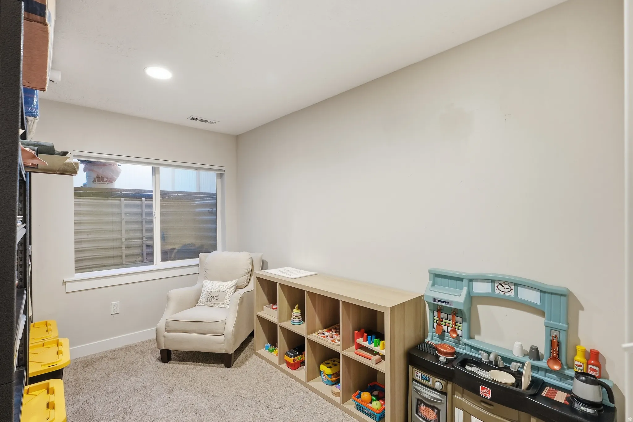 Recessed ceiling lighting, light-toned carpeting, a window with exterior grating, and light-toned walls