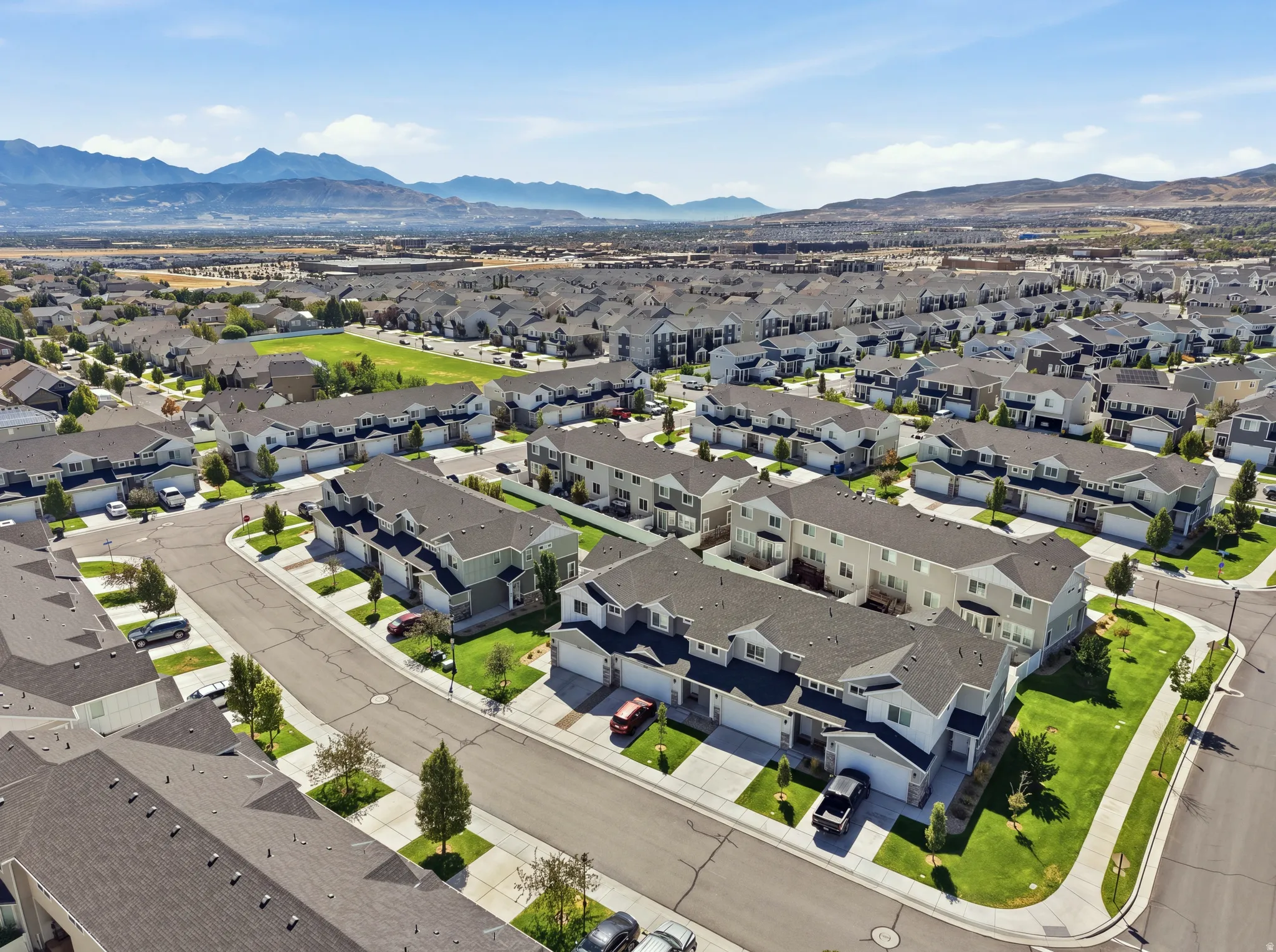 Townhome community with extensive green spaces and paved streets, featuring mountain scenery