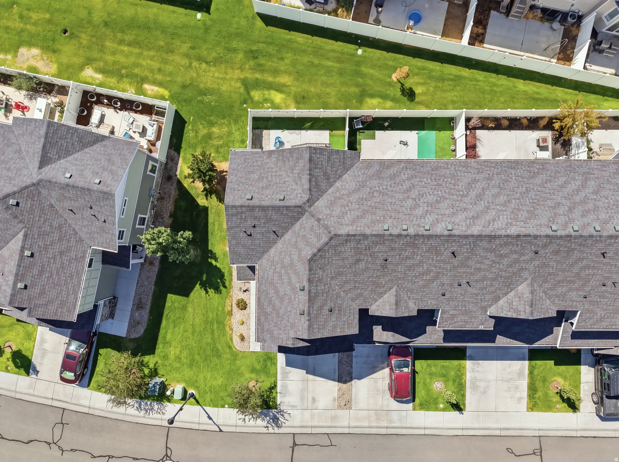 Asphalt shingle roof, concrete driveways, manicured lawns, and fenced backyards