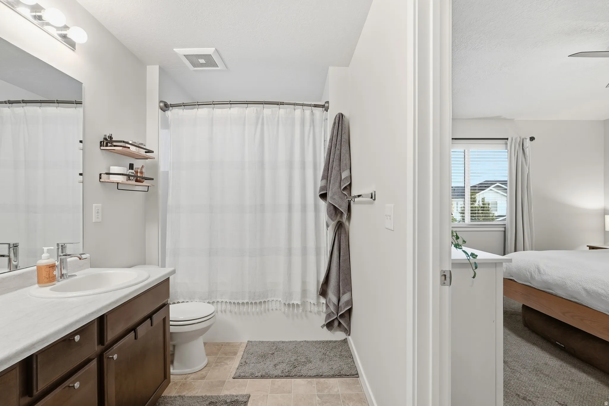 Bathroom vanity with a single basin sink, chrome faucet, and integrated mirror