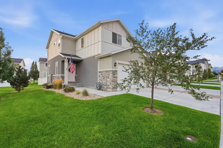 Modern two-story exterior with stone veneer accents, an attached garage, and a concrete driveway