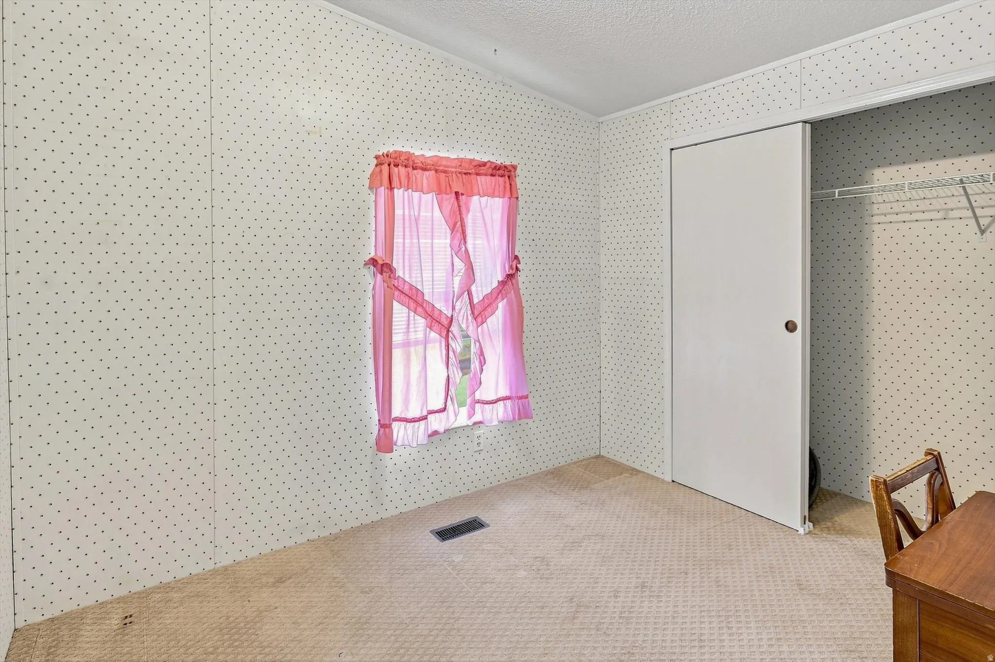 Sliding closet door, wire shelving system, patterned wall covering, carpeted flooring, window with natural light