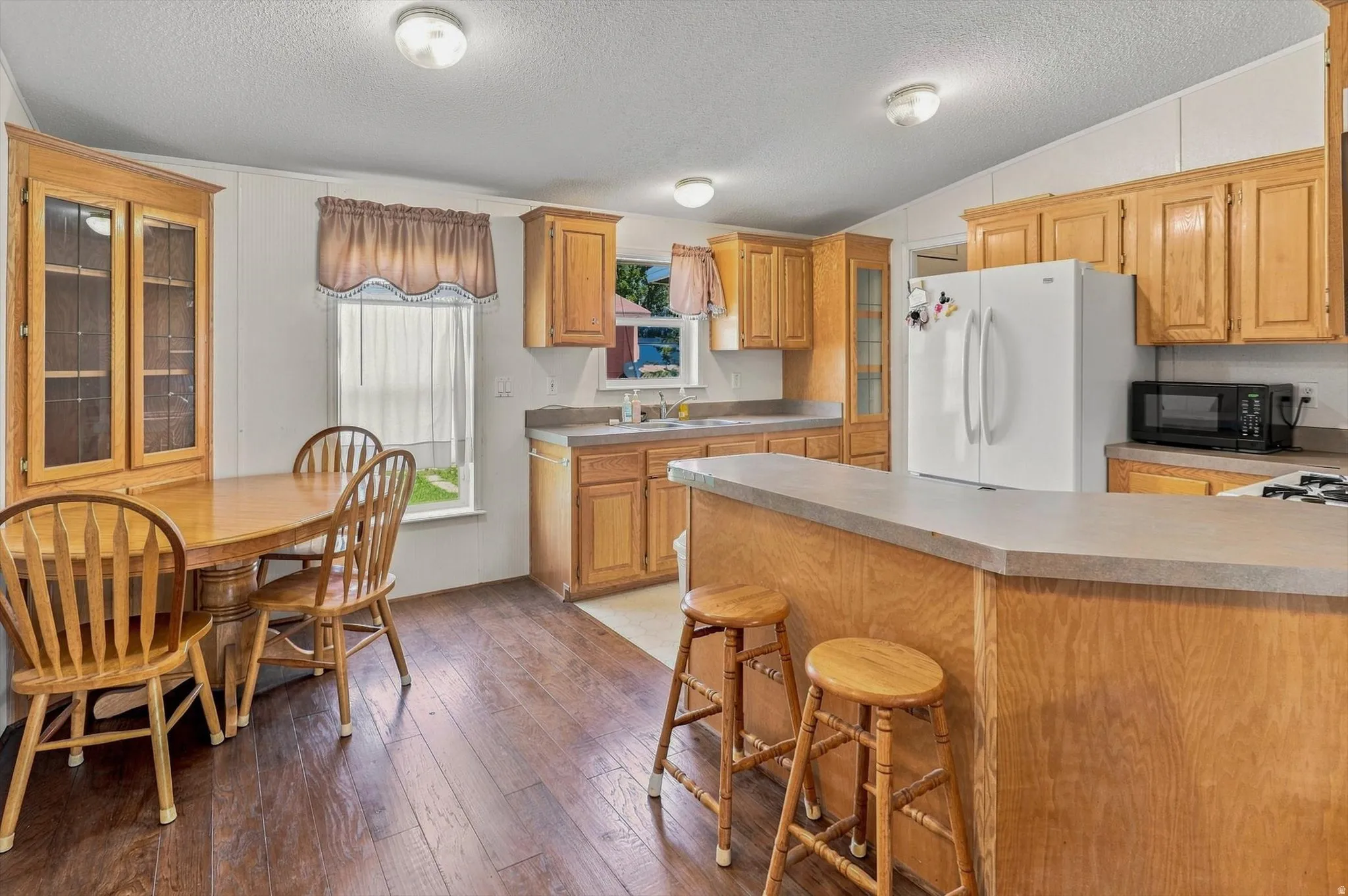 Kitchen featuring wood-finish flooring, wood cabinetry, built-in display cabinet, and a breakfast bar with solid surface countertops