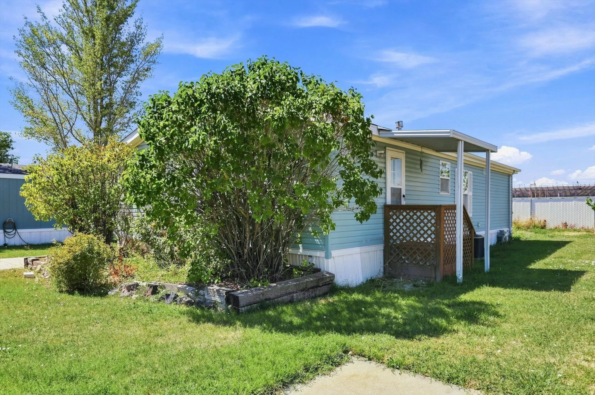 Exterior featuring light blue siding, a covered entry, and a lattice privacy screen