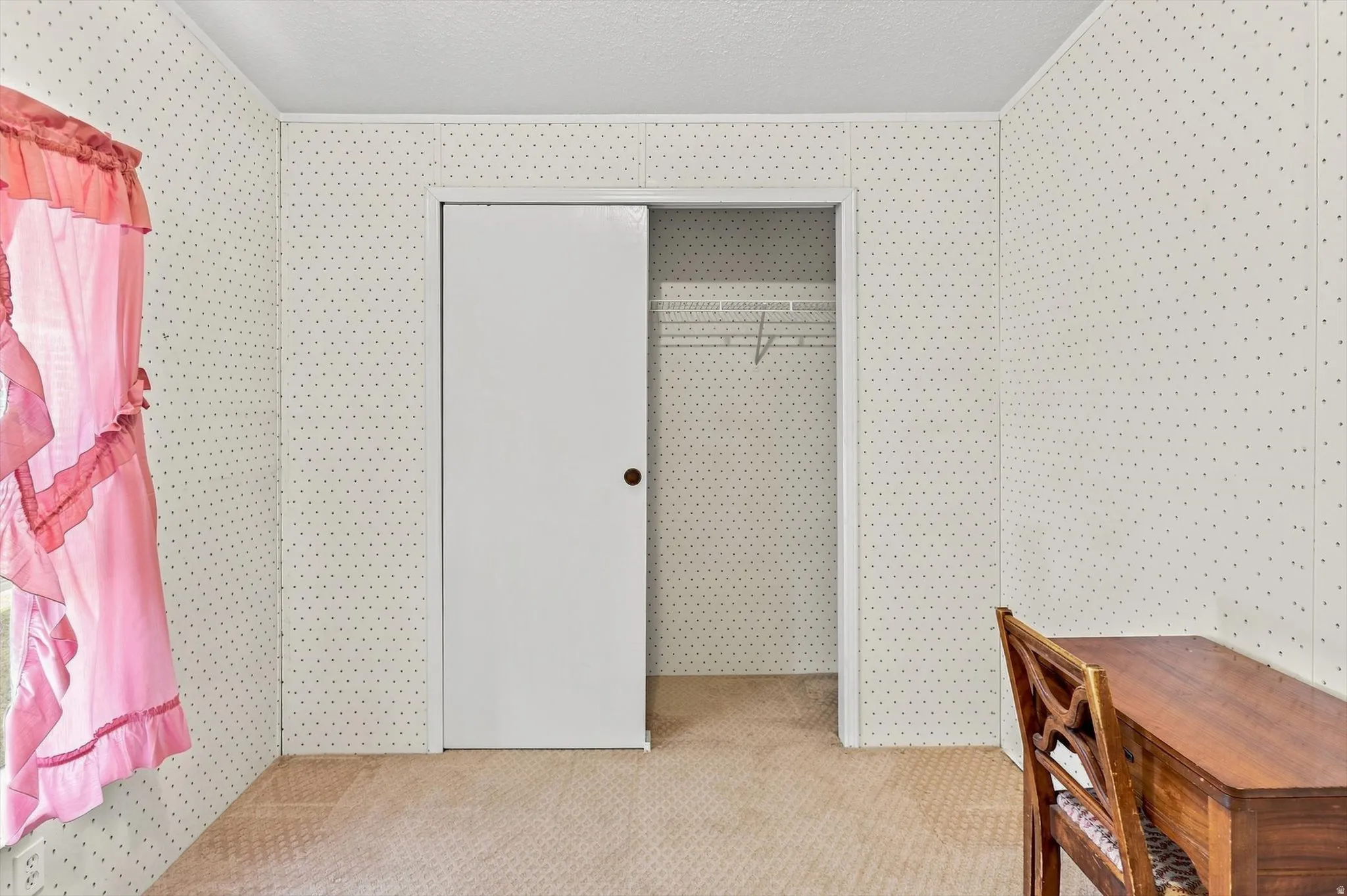 Room featuring textured wall panels, a sliding closet door, and wire shelving within the closet