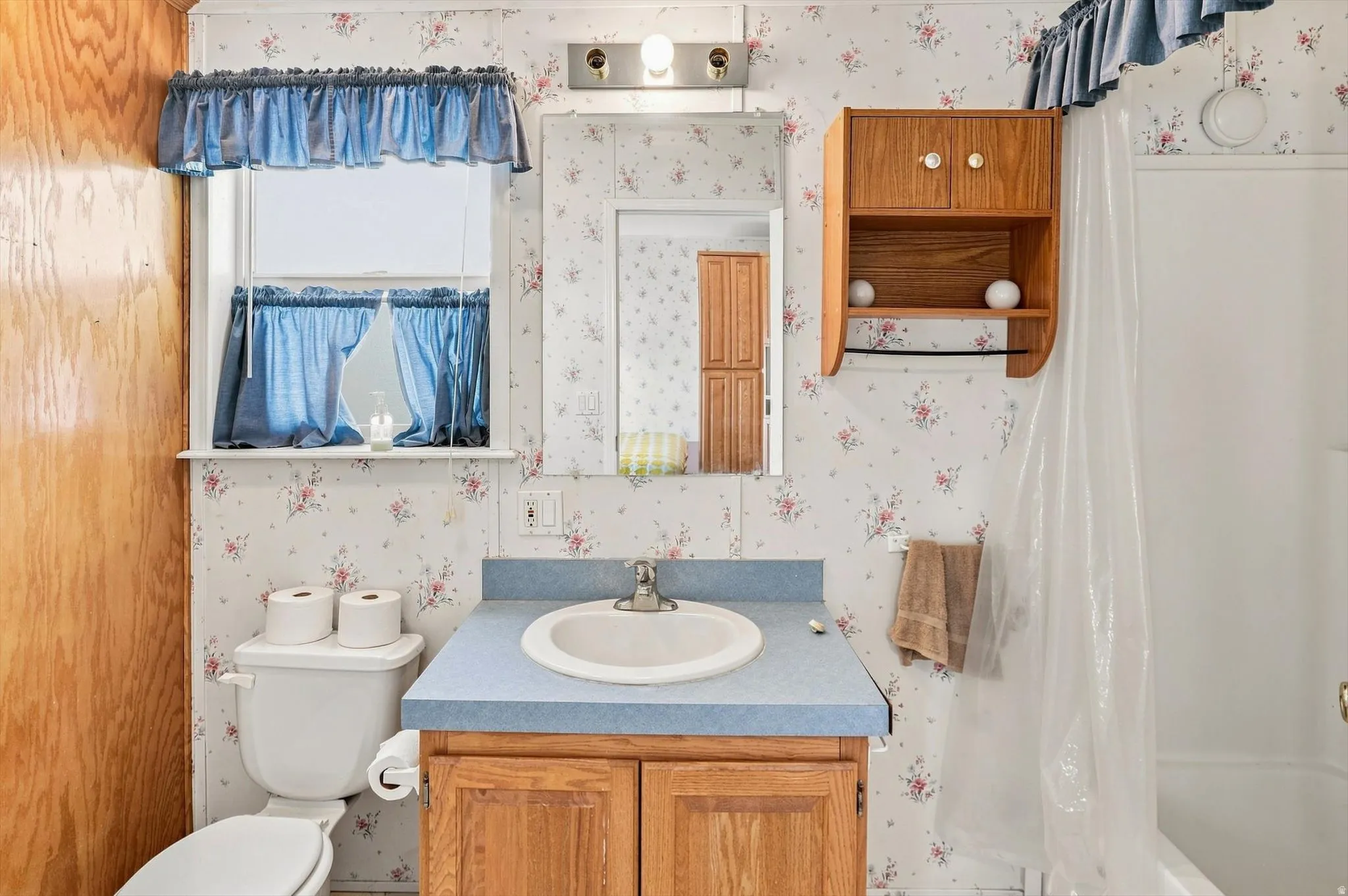 Built-in wooden vanity with a laminate countertop, integrated sink, and an overhead medicine cabinet with mirrored door