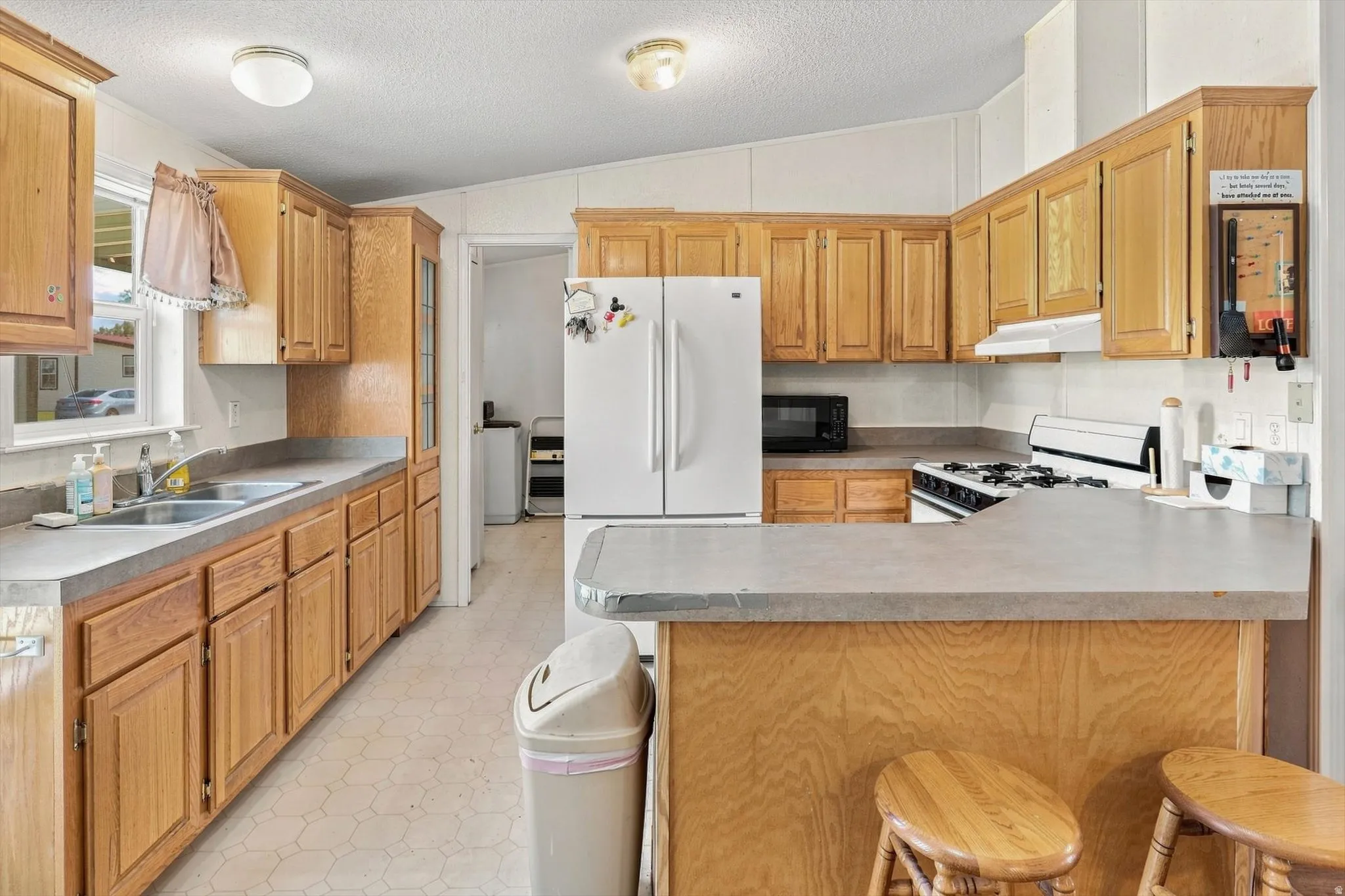 Spacious kitchen featuring warm wood cabinetry, stainless steel appliances, and a large center island with wood-finish base and seating for two