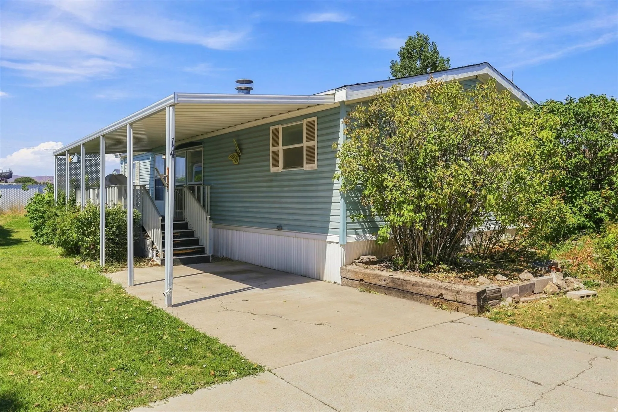 Covered entryway with steps, concrete driveway, and established perimeter landscaping