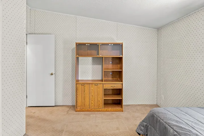 Textured wall paneling, light-toned carpeting, and a white interior door