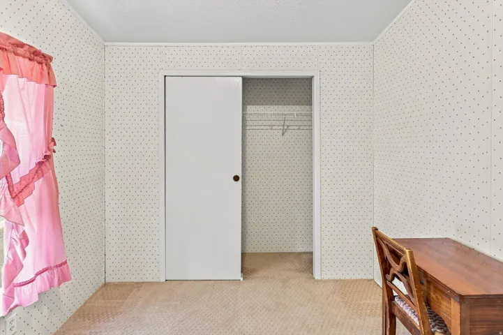 Room featuring textured wall panels, a sliding closet door, and wire shelving within the closet