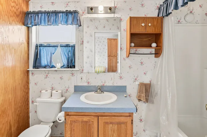 Built-in wooden vanity with a laminate countertop, integrated sink, and an overhead medicine cabinet with mirrored door