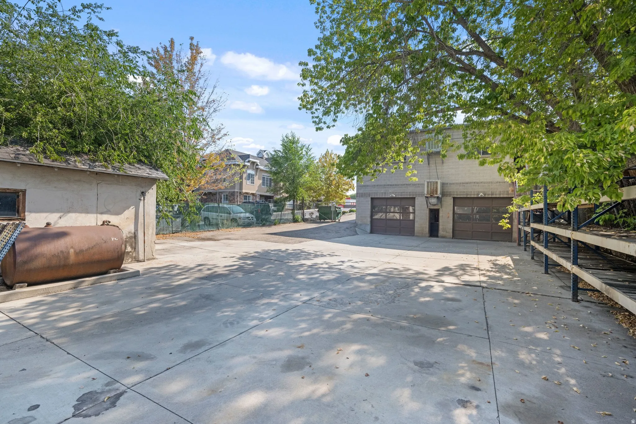 Paved lot with two roll-up garage doors, brick facade, and a separate outbuilding