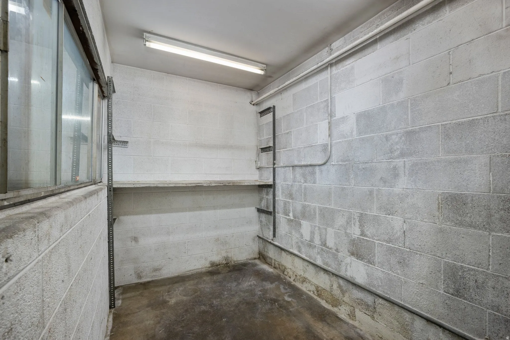 Concrete block walls with utility piping, a built-in shelf, and strip lighting