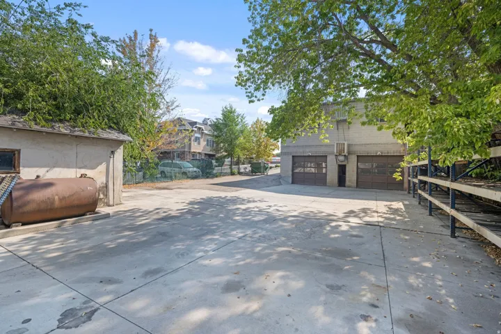 Paved lot with two roll-up garage doors, brick facade, and a separate outbuilding
