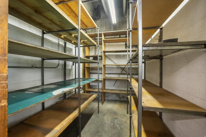 Extensive built-in wood shelving units, metal shelving supports, concrete block walls, and overhead fluorescent lighting