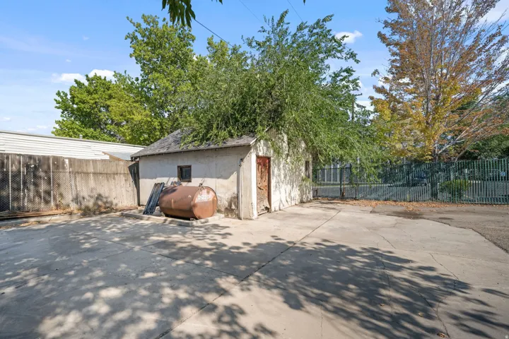 Concrete paved area with a detached structure featuring a window and metal door