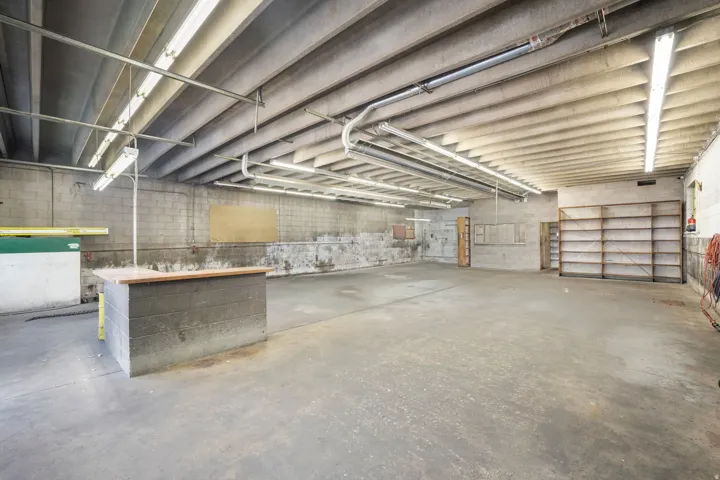 Expansive concrete flooring throughout, exposed concrete block walls, overhead fluorescent lighting, and built-in shelving