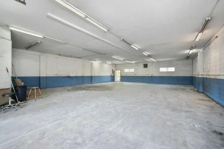 Expansive concrete flooring with a neutral wall palette, featuring multiple fluorescent light fixtures
