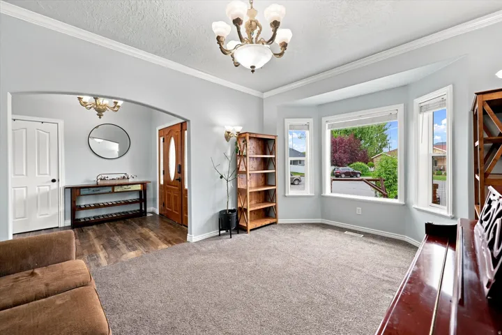 Expansive bay window, archway entry, wood-finish flooring, white paneled interior door, and a decorative chandelier