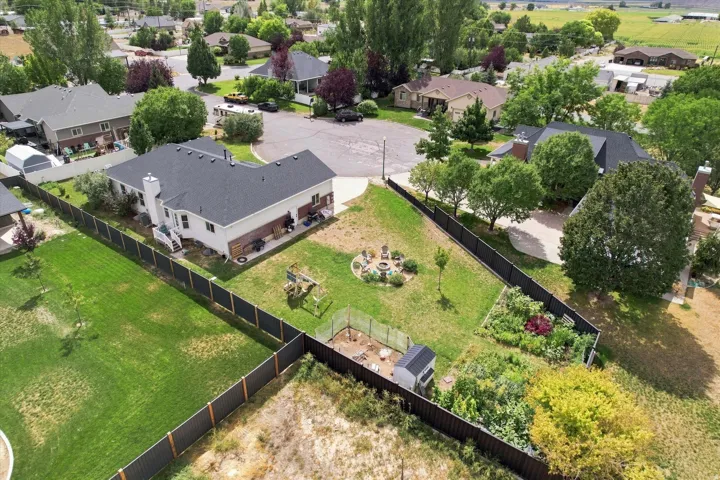 Expansive backyard with a manicured lawn, established garden beds, and mature trees
