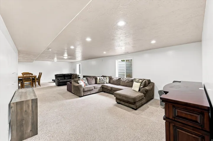 Recessed lighting illuminates the expansive carpeted space, featuring multiple egress windows and a built-in media console