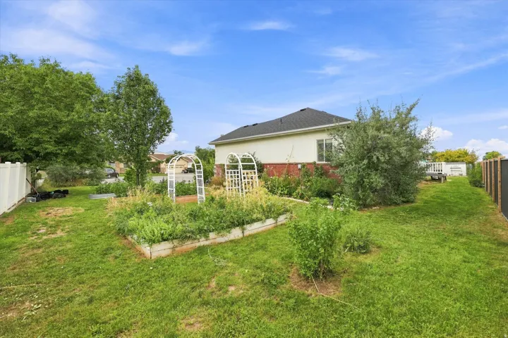 Expansive lawn area featuring a raised garden bed, decorative arbors, and mature landscaping