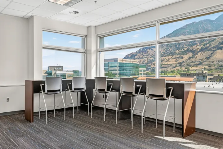 Full-height windows with mountain scenery, recessed lighting, and patterned carpeting