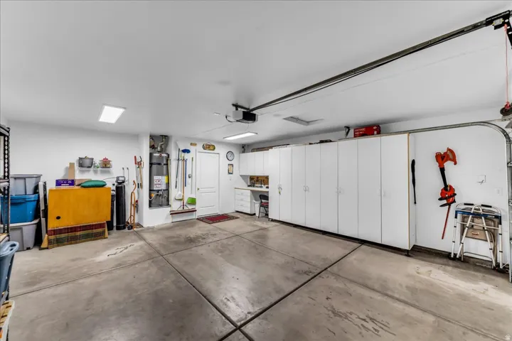 Attached garage with concrete flooring, extensive built-in white cabinetry, and recessed lighting