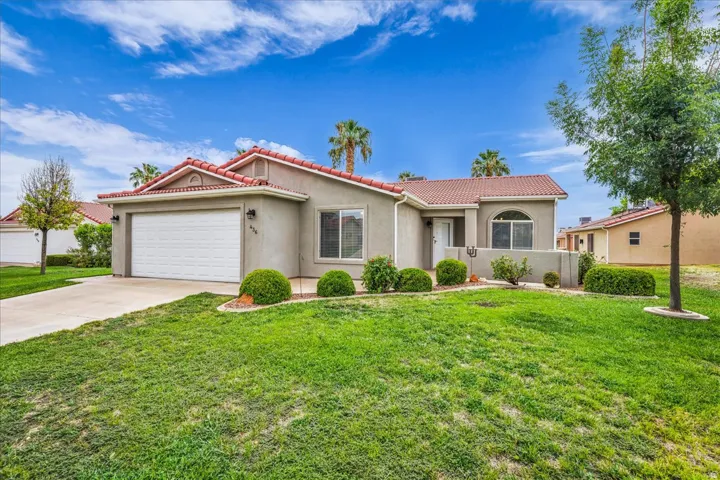 Stucco exterior with a terracotta tile roof, attached two-car garage, concrete driveway, and front landscaping