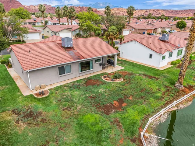Terracotta tile roof, stucco exterior, rear patio, water feature, and landscaped yard