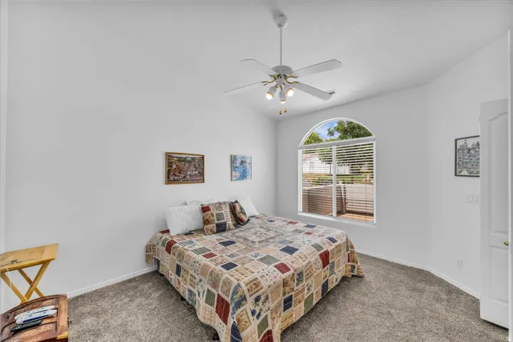Arch-top window with horizontal blinds, ceiling fan with integrated lighting, recessed door, and neutral wall color