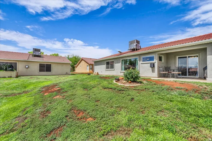 Expansive backyard featuring a patio, sliding glass door access, and a decorative landscape bed
