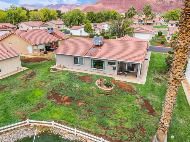 Red tile roofing, covered patio, white fencing, rock landscaping, and mature trees