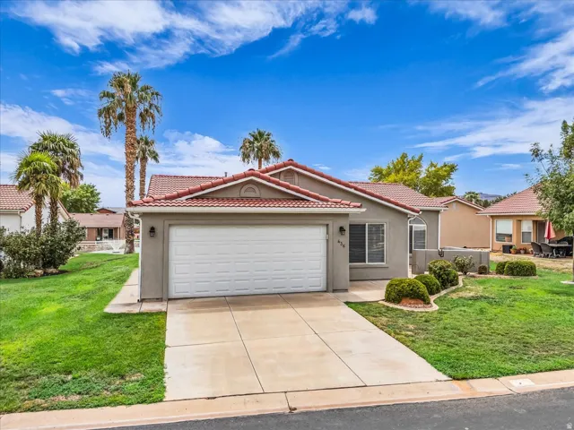 Stucco exterior with a tile roof, an attached two-car garage, and a concrete driveway