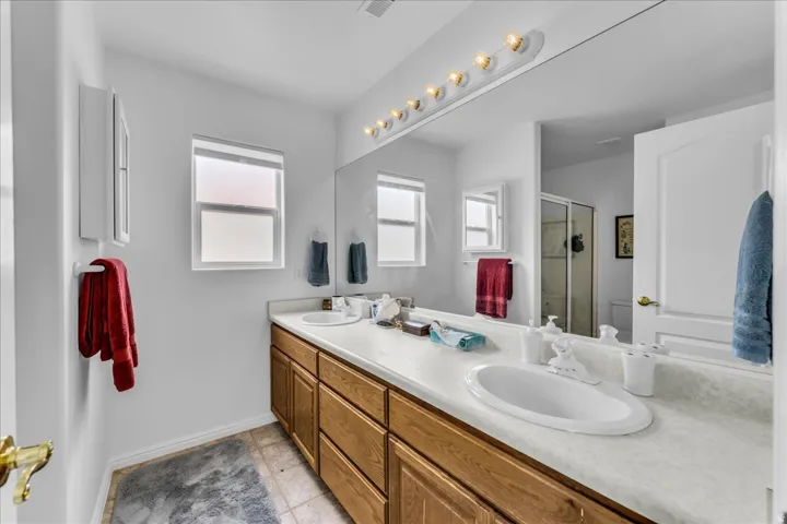 Double vanity with integrated sinks, wood-finish cabinetry, and a full-width mirror